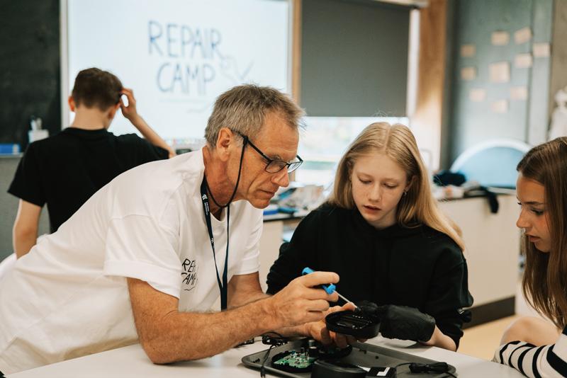 Underviser hjælper elever med at reparere et produkt